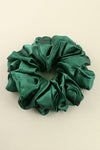 Green satin scrunchie on a beige background