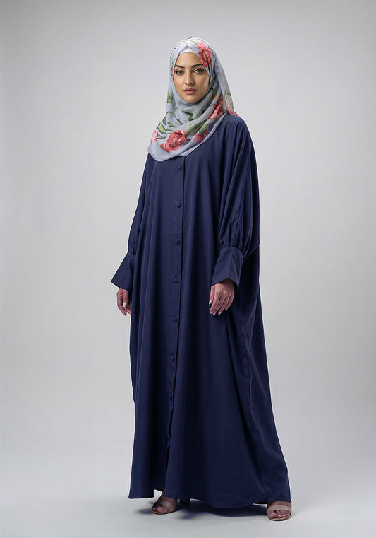 Woman wearing a long navy dress and a floral hijab on a white background