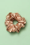 Pink satin scrunchie on a light green background