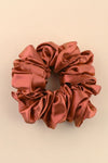 Reddish-brown satin scrunchie on a beige background