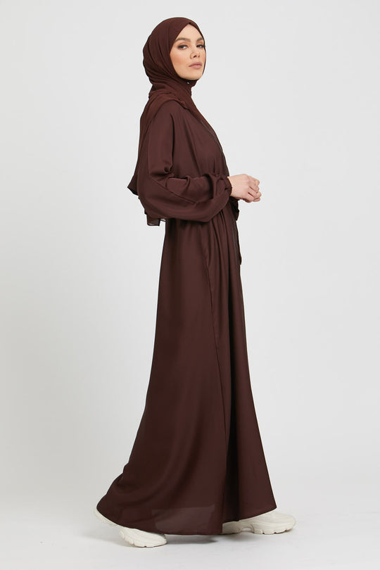 Side full view of brown kimono abaya styled with white slip dress, modest fashion abaya with cuff sleeves for women in Pakistan
