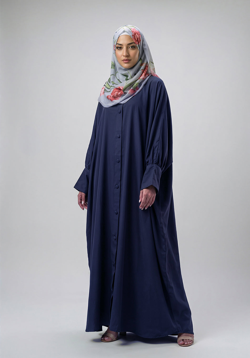 Woman wearing a long navy dress and a floral hijab on a white background