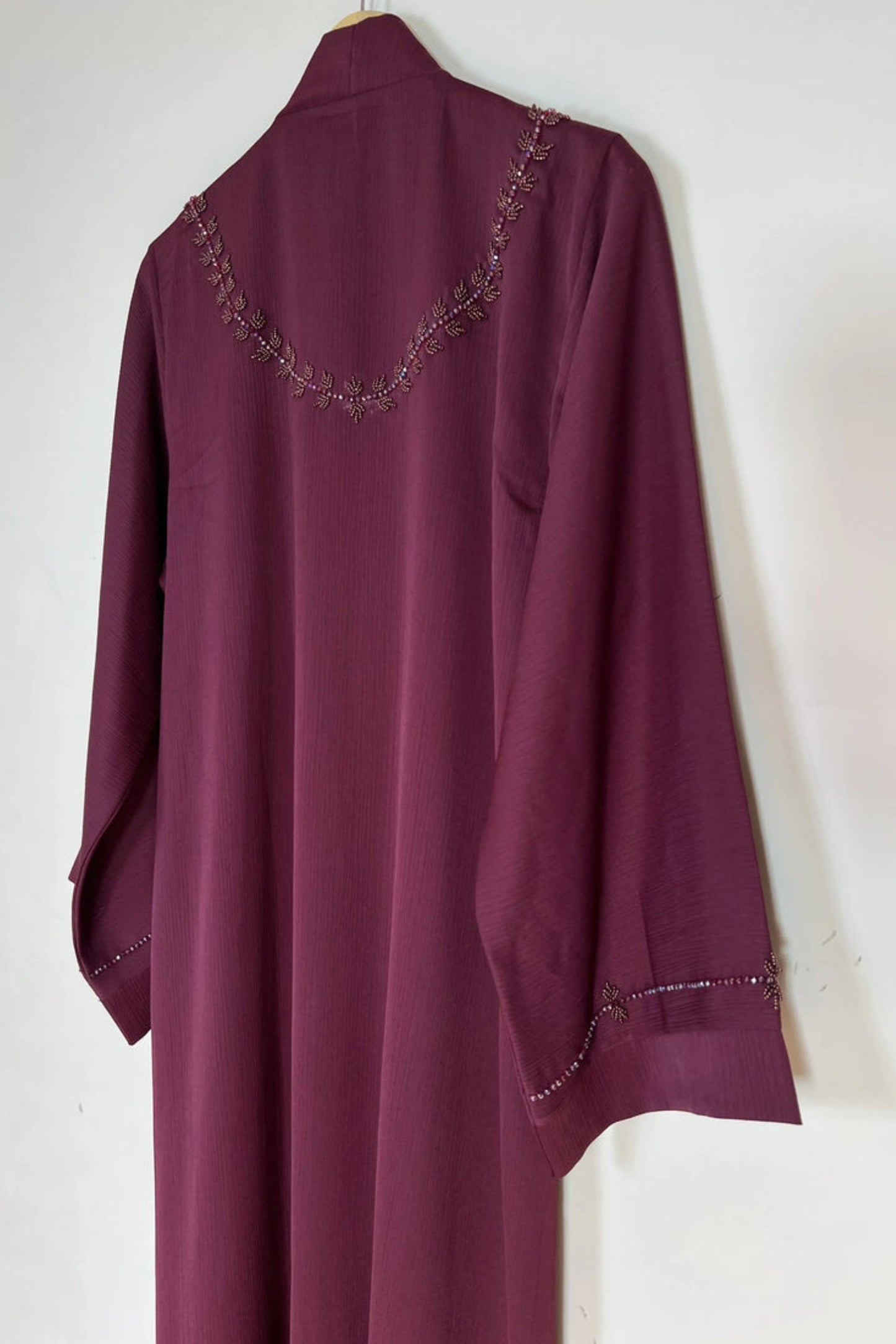 Back side full view of maroon premium nida abaya hanging on hanger showing smooth fall and modest elegant finish